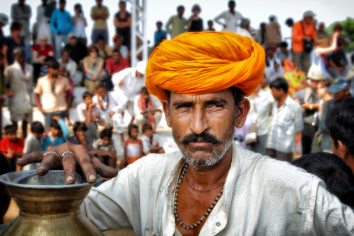Pushkar, India - November 15, 2010: Indian tea seller at Pushkar Camel Fair. Man with his tea urn in the parade ring with lots of spectators standing in the background