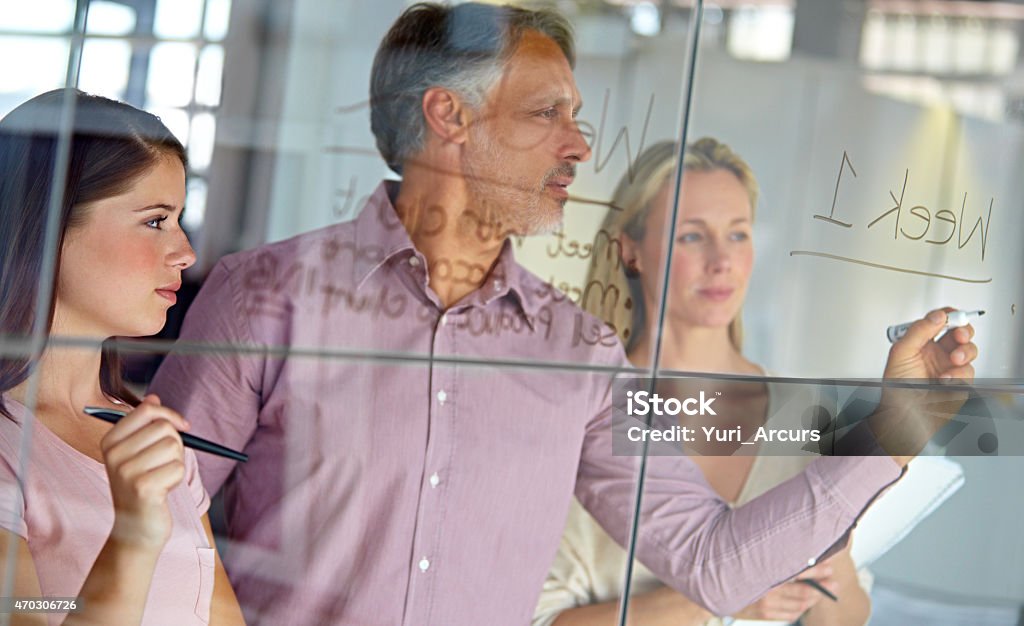 Setting up a schedule for their latest project A mature businessman writing down plans on a glass pane while his colleagues look onhttp://195.154.178.81/DATA/i_collage/pi/shoots/781785.jpg Corporate Business Stock Photo