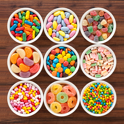 Top view of nine bowls with different types of multicolored candy