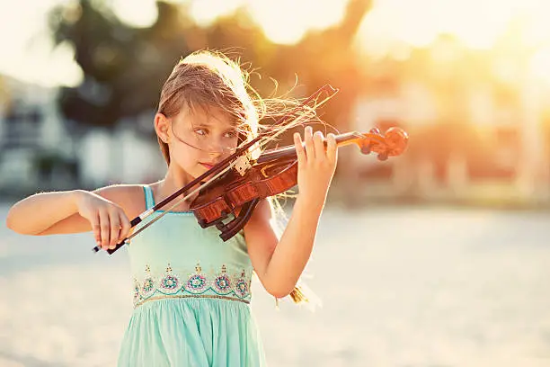 Photo of Music of the summer - girl playing violin on beach