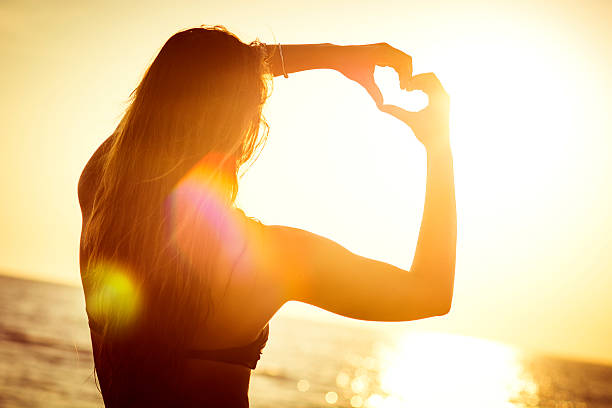istock Female at the beach making a heart symbol with her hands 470310276