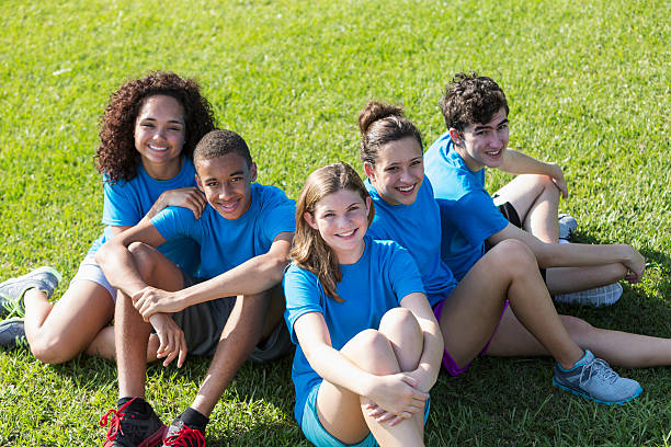istock Teenagers in blue t-shirts sitting on grass 470310496