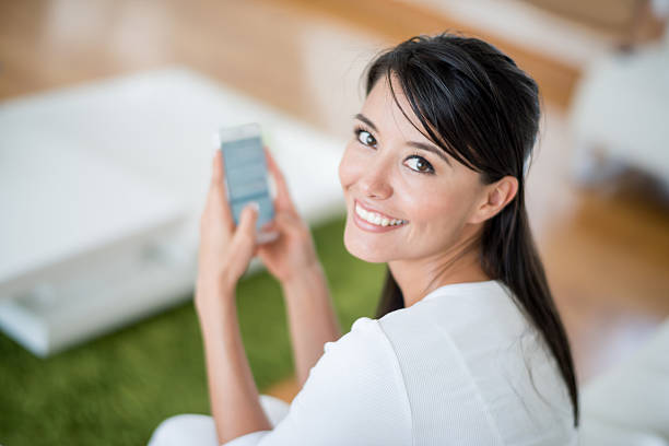 Woman at home texting on the phone but looking at the camera