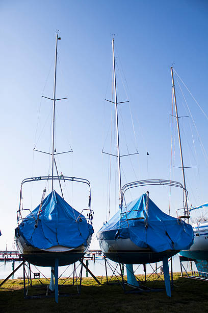 sailboats stored in a marina, covered in blue shrink wrap plastic, to protect them over the winter
