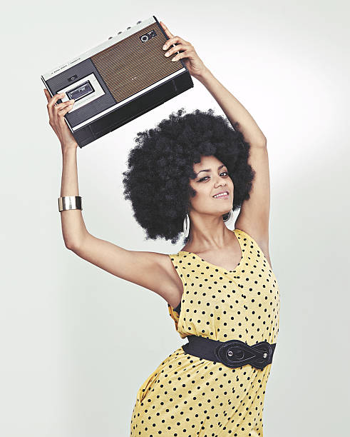 A young woman wearing a 70s retro jumpsuit holding a cassette player and striking a disco posehttp://195.154.178.81/DATA/i_collage/pi/shoots/782690.jpg