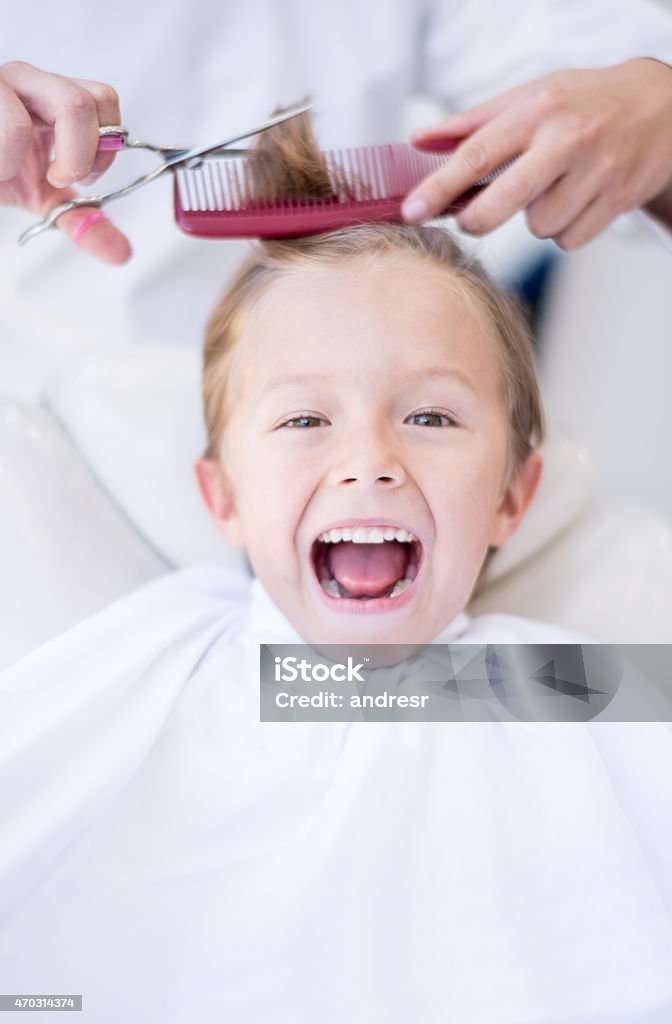 Boy at the hairdresser Boy at the hairdresser getting a haircut and looking scared or excited Child Stock Photo