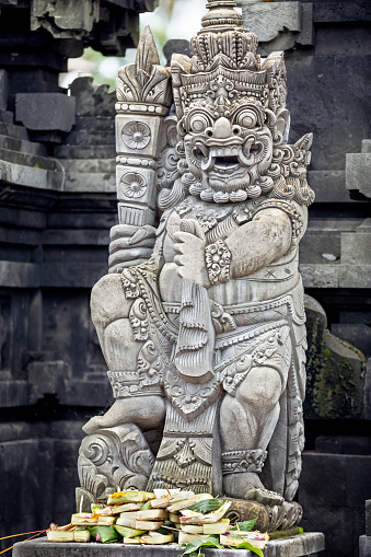 Statues and carvings depicting demons or gods with offerings in Ubud, Bali.
