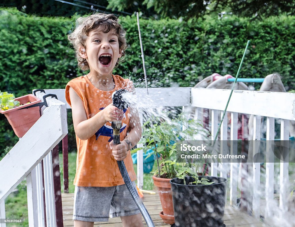 Little boy watering everyone with a hose A boy watering everyone with a hose Garden Hose Stock Photo