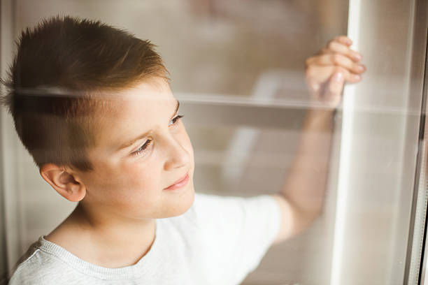 istock Portrait of a boy looking through the window 470321500