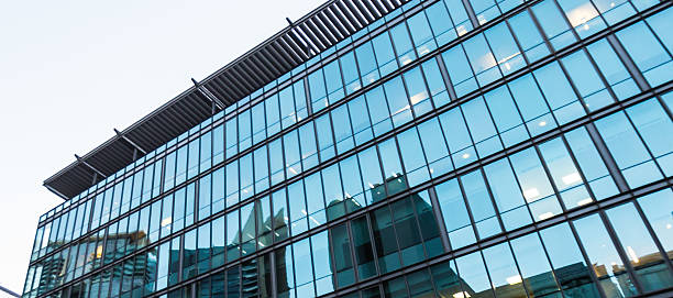 Business Building in Downtown Dubai Business Building in Downtown Dubai on a clear day; showing detail from a modern building, glass and metal structure. With a clear reflective glass plane view of its opposing towers. architecture textured effect architectural feature business stock pictures, royalty-free photos & images