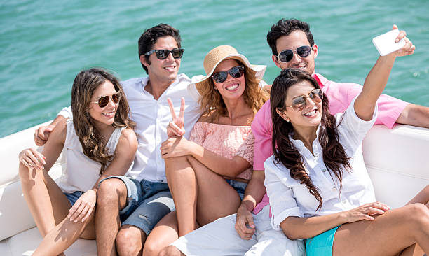 Friends sailing on a boat and taking a selfie Group of friends sailing on a boat in the summer and taking a selfie yacht selfie stock pictures, royalty-free photos & images