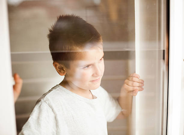 istock Portrait of a boy looking through the window 470329644