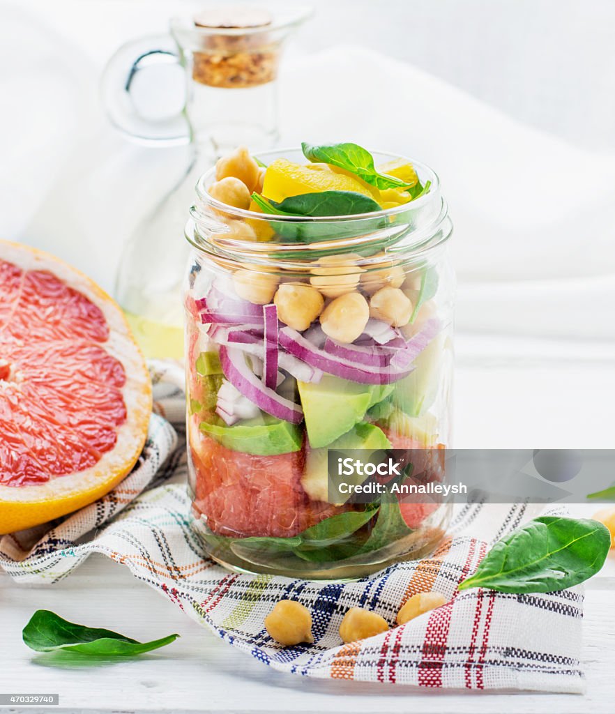 Delicious salad put into a jar for easy transport Fresh spring salad of grapefruit, avocado, sweet onion, spinach and chickpeas in a glass jar for a snack with you on a picnic in the country, to work. The concept of healthy proper nutrition for the whole family. selective Focus 2015 Stock Photo