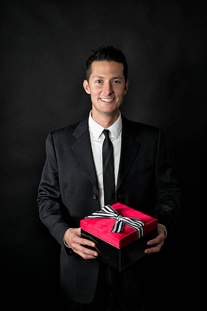 istock Man in black suit holding a gift box 470338395