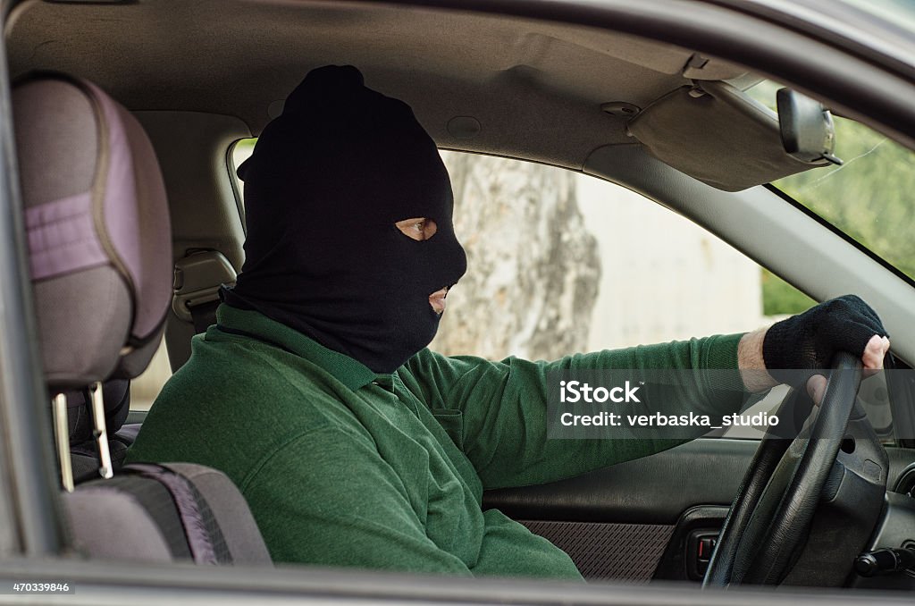 Robber in balaclava inside a car Bank robber in black balaclava waiting inside a car Bank Robber Stock Photo