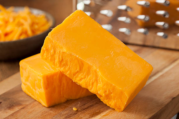 Organic Sharp Cheddar Cheese Organic Sharp Cheddar Cheese on a Cutting Board cheddar cheese stock pictures, royalty-free photos & images