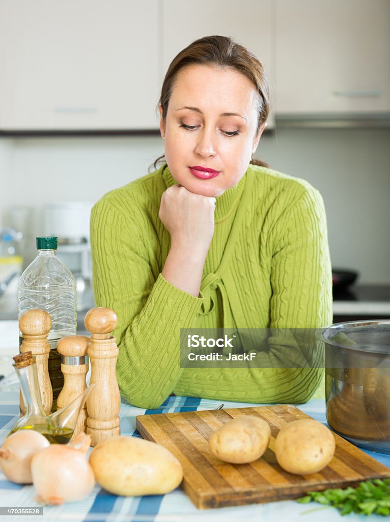 Tired housewife at kitchen Tired brunette woman preparing soup at domestic kitchen 2015 Stock Photo