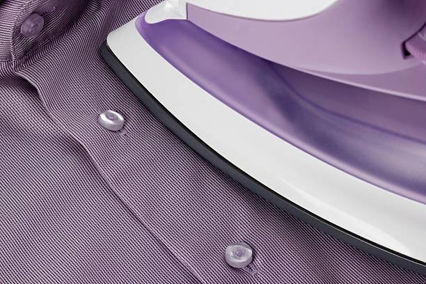 istock smoothing-iron on purple shirt with selective focus 470357149