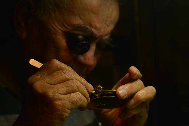 Watchmaker working An old watchmaker working with magnifying glass and clockwork items broken pocket watch stock pictures, royalty-free photos & images