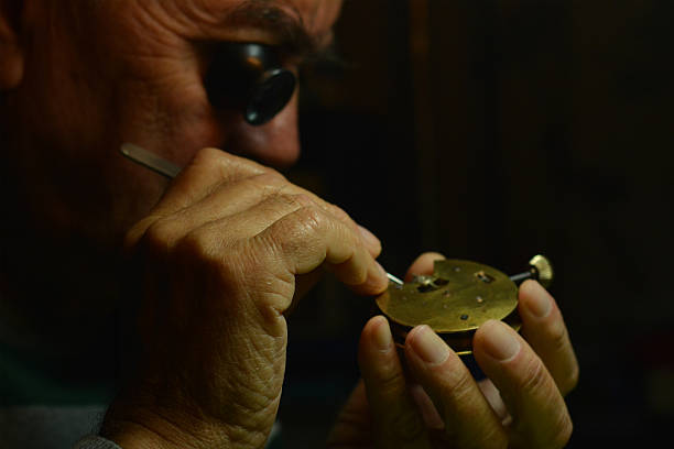 Watchmaker working An old watchmaker working with magnifying glass and clockwork items broken pocket watch stock pictures, royalty-free photos & images