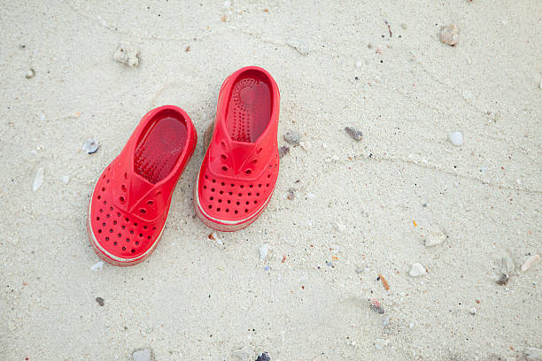 istock Red children shoeson beach 470373226