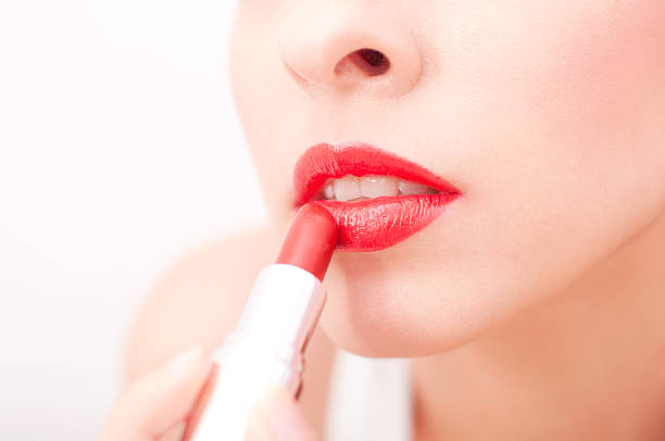 istock Beautiful woman applying lipstick 470392421