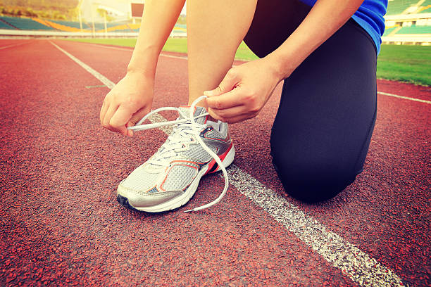 istock woman runner tying shoelaces on track 470403750