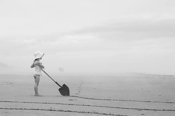 Little Girl Drawing Tacks in Sand On Misty Beach