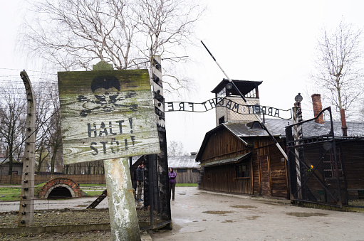 Oswiecim, Poland - April 3, 2015: The main entrance gate to Auschwitz concentration camp, Poland. It was the biggest nazi concentration camp in Europe during World War II, Stop sign in front. 