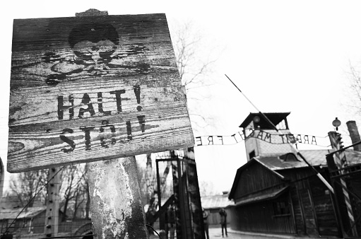 Oswiecim, Poland - April 3, 2015: The main entrance gate to Auschwitz concentration camp, Poland. It was the biggest nazi concentration camp in Europe during World War II, Stop sign in front. 