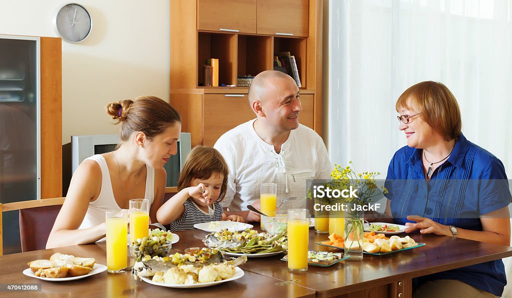 multigeneration family  eating fish with vegetables multigeneration family  eating fish with vegetables at home together 2015 Stock Photo