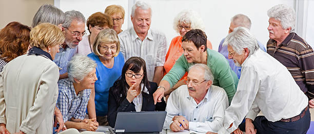 Group of seniors at computer workshop, panoramic.