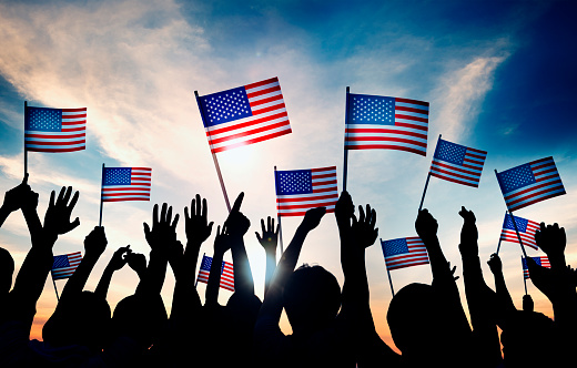 Group of People Waving American Flags in Back Lit