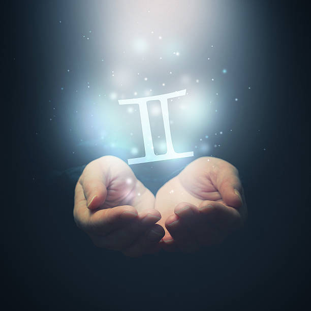 Female hands opening to light and holding zodiac sign for Gemini. Horoscope symbols set. Selective focus.