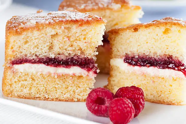 Victoria sponge cake with cream and jam filling, served with raspberries