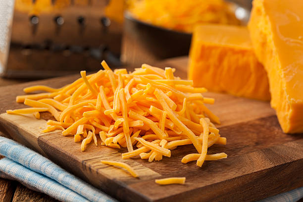 Organic Shredded Sharp Cheddar Cheese Organic Shredded Sharp Cheddar Cheese on a Cutting Board cheddar cheese photos stock pictures, royalty-free photos & images