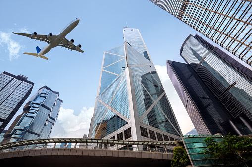Tall city buildings and a plane flying overhead, Hong Kong