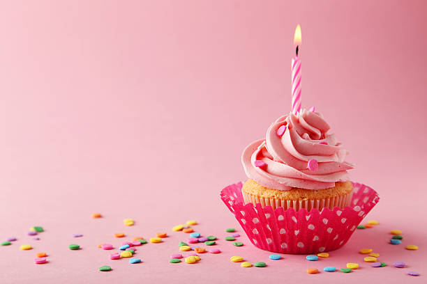 istock Tasty cupcake with candle on pink background 470441106