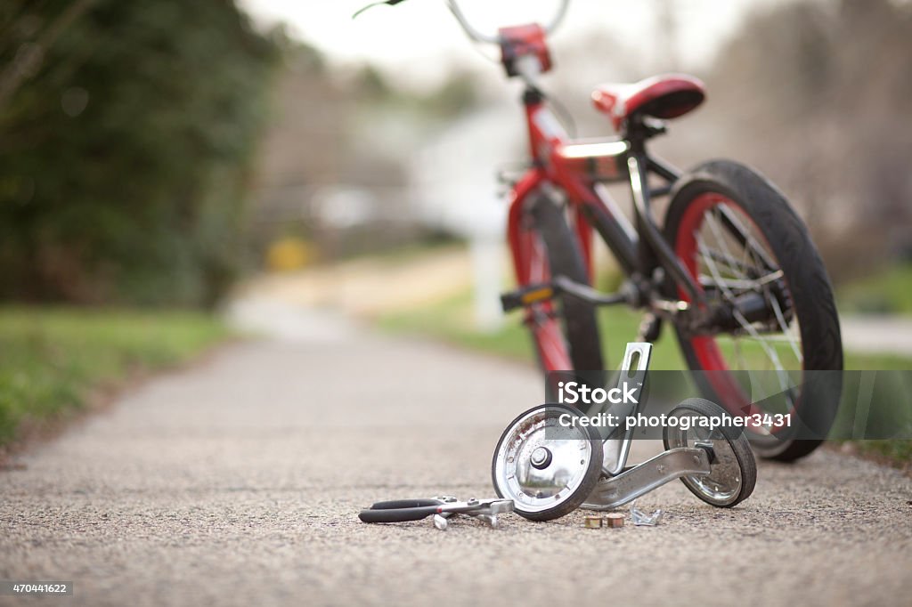 Training wheels taken off bike Set of training wheels taken off of a child's bicycle with some tools laying on the ground. Absence Stock Photo