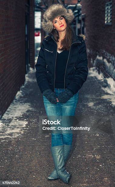 Pretty Model In Snow Wearing Furry Winter Hat In Alley Stock Photo - Download Image Now
