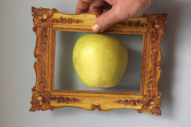 an apple inside a frame is holded by a hand