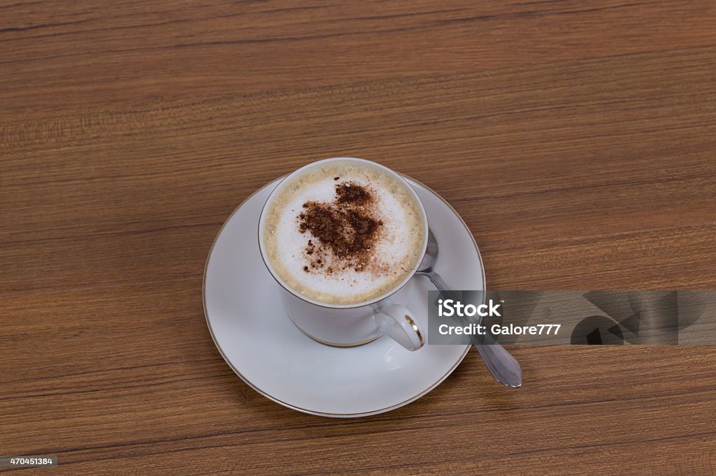 Cuppaccino in a Cup on Brown Woodgrain Background Cuppaccino in a Cup on Brown Woodgrain Background Isolated in Studio with High View and with Selective Focus using Macro 2015 Stock Photo