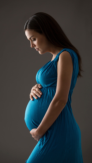 A beautiful pregnant woman holding her belly and looking at it.