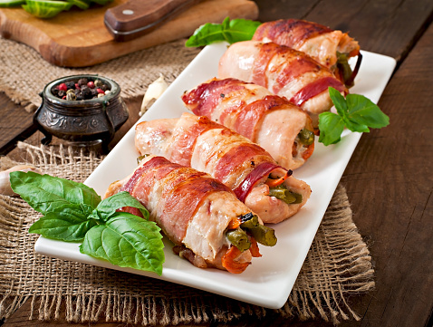 Delicious chicken rolls stuffed with green beans and carrots wrapped in strips of bacon