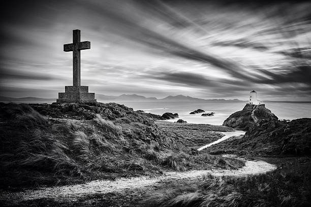 Cross and Lighthouse on Ynys Llanddwyn, Anglesey, Wales stock photo