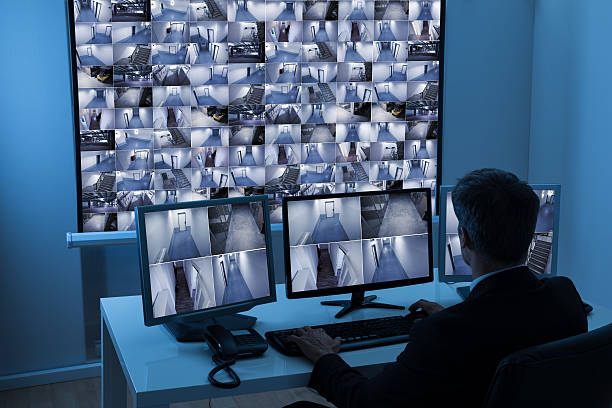 Man In Control Room Monitoring Cctv Footage Rear View Of A Man In Control Room Monitoring Multiple Cctv Footage security guard photos stock pictures, royalty-free photos & images