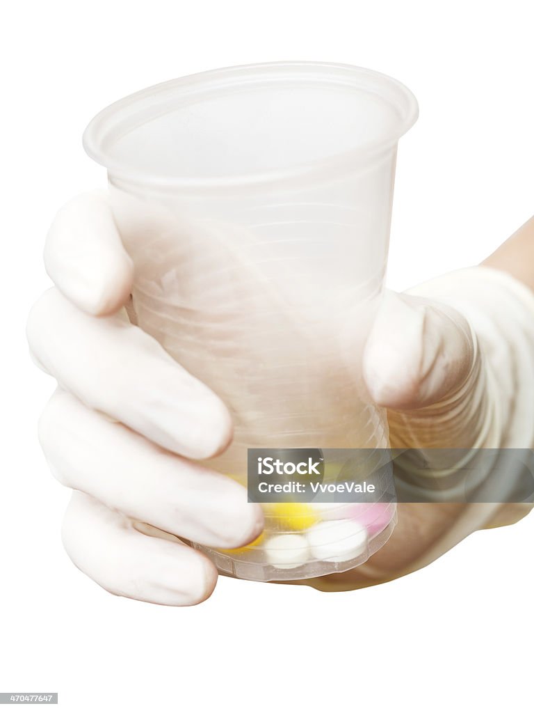 Una mano de sujeción de plástico taza con pastillas - Foto de stock de Asistencia sanitaria y medicina libre de derechos