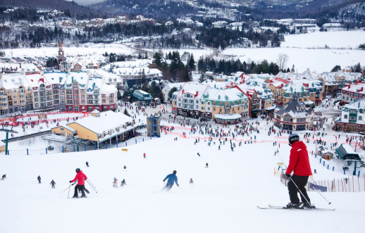 Mont-Tremblant, Canada - February 9, 2014:  Skiers and snowboarders are sliding down the main slope at Mont-Tremblant. Mont-Tremblant Ski Resort is acknowledged by most industry experts as being the best ski resort in Eastern North America.