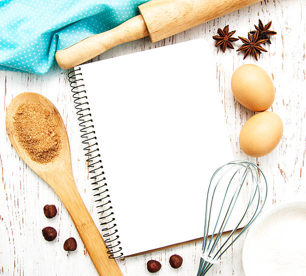 Blank recipe book with cooking utensils, spices and eggs