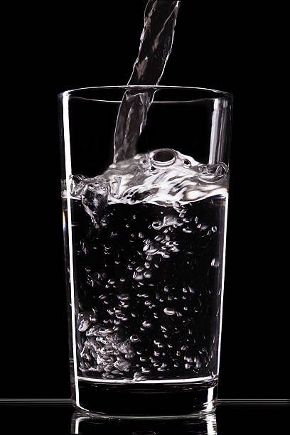 istock Pouring water into glass on black  background 470492801